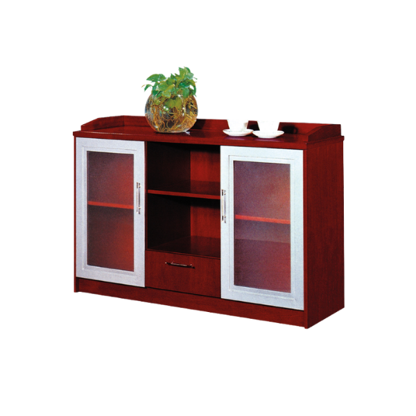 Wooden cabinet with a polished reddish-brown finish, featuring two glass-paneled doors with metallic frames and handles on each side, a central open shelf, and a drawer below with a metallic handle. On top, a round glass vase with a green leafy plant and two white teacups with saucers add a decorative touch, blending functionality with modern design.
